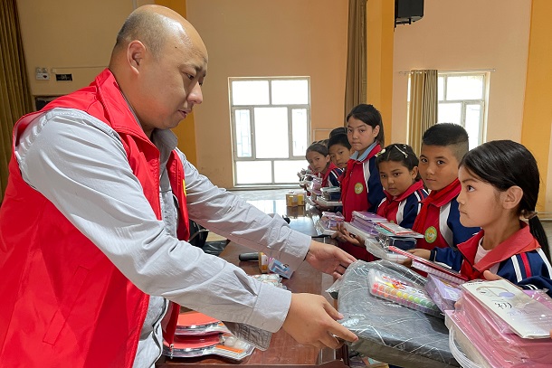 图为张成国给学生赠送文具